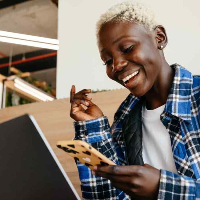 Smiling man at a table with a laptop and phone